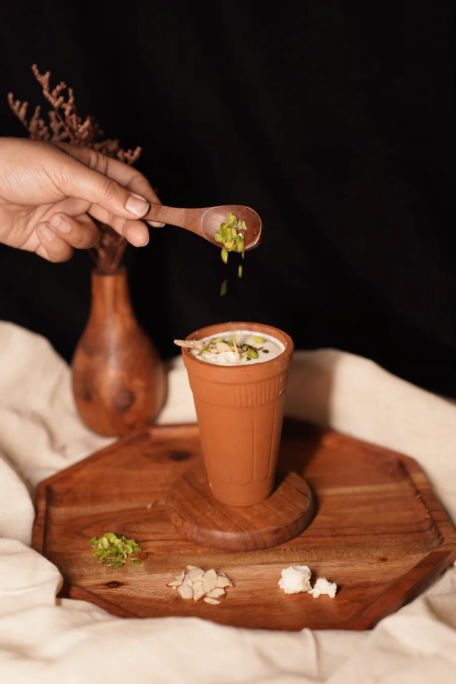 Pistachio being sprinkled over a lassi